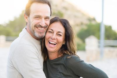 Middle aged man and woman holding each other and smiling after dental inlays, Roseville NSW