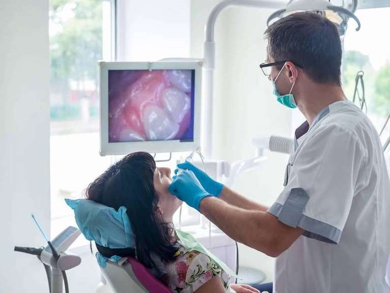 Woman sitting in dentist patient chair while a dentist looks at her teeth with an intraoral camera, Roseville NSW